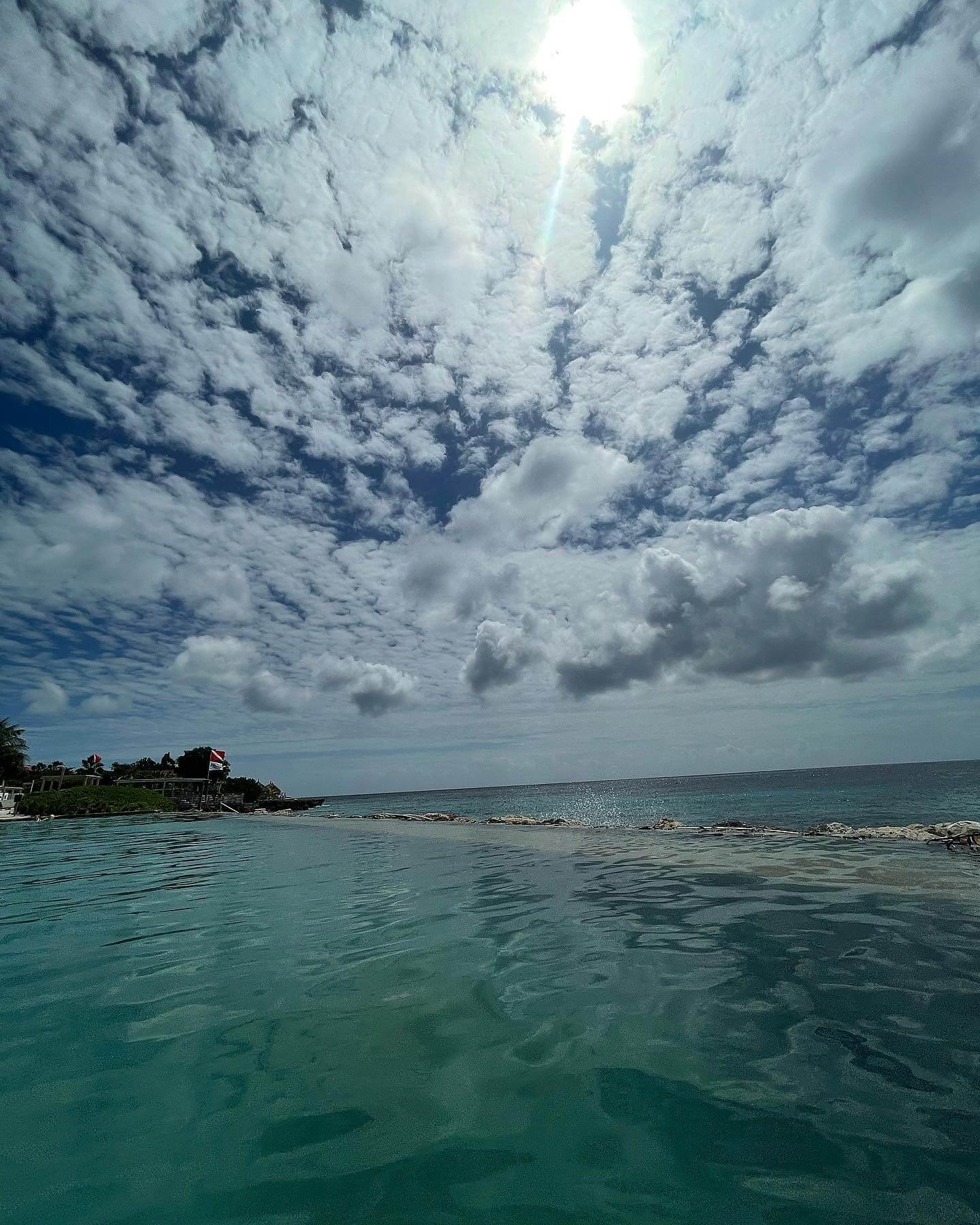 Vista panorámica de una playa paradisíaca con aguas turquesas y cielo parcialmente nublado, ideal para ilustrar consejos sobre qué llevar en la maleta de viaje para destinos tropicales.