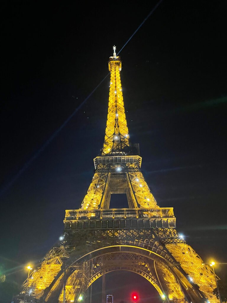 Torre Eiffel iluminada de noche en París, Francia en Europa vista desde la base con luces doradas y cielo oscuro estrellado . Foto tomada por Valen para su blog de viajes