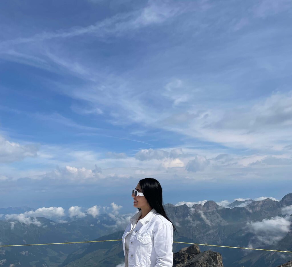 Viajera disfrutando de una vista panorámica en los Alpes Suizos, representando la libertad de viajar con hospedaje económico.
