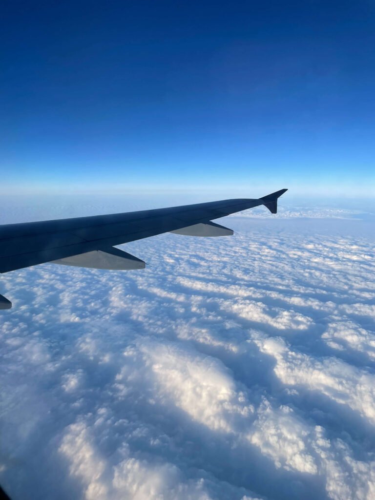 Fotografía tomada por una viajera desde un avión sobrevolando un mar de nubes blancas con cielo despejado y azul