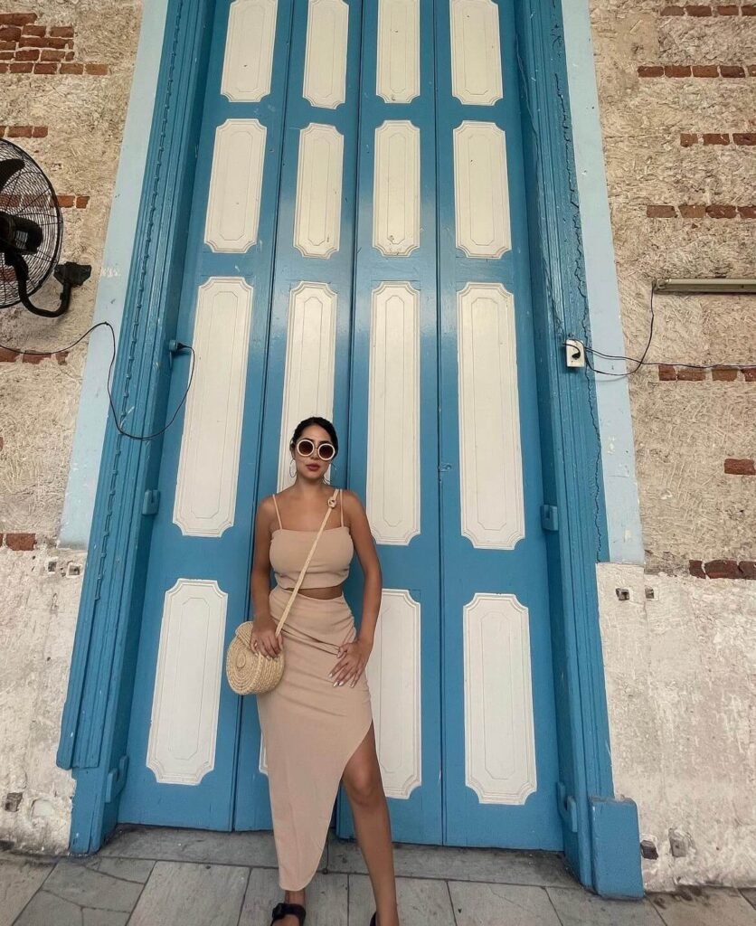 Viajera Con un estilo frente a una de las icónicas puertas azules de La Habana, capturando la esencia vibrante y colorida de Cuba.