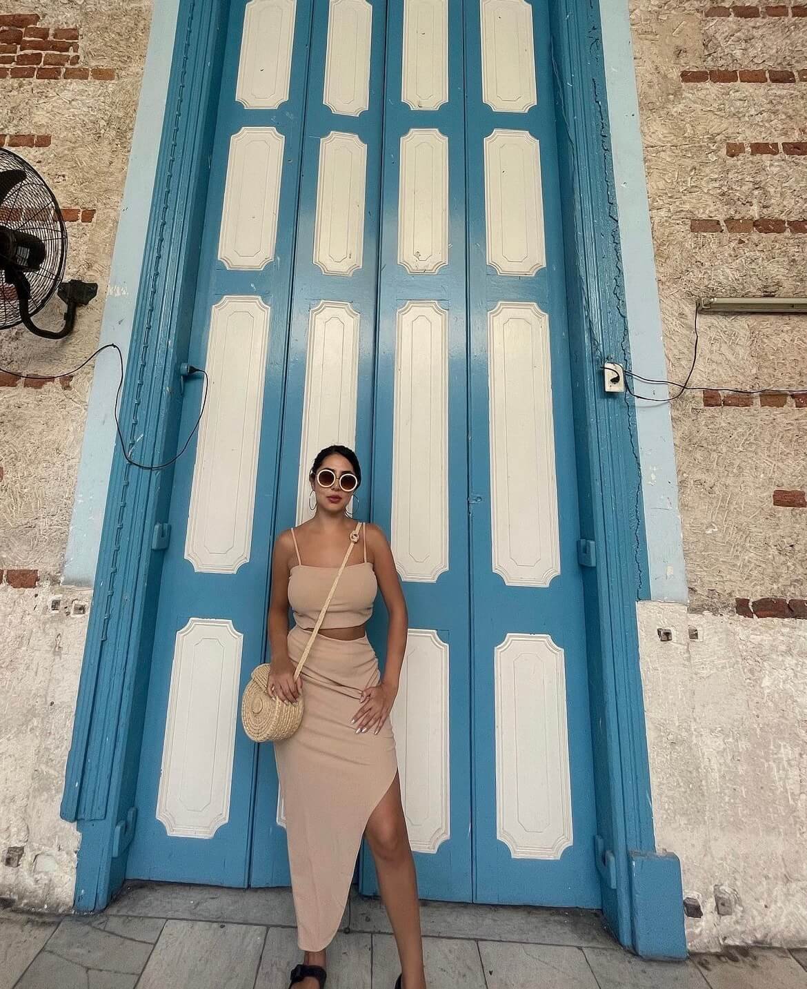 Viajera Con un estilo frente a una de las icónicas puertas azules de La Habana, capturando la esencia vibrante y colorida de Cuba.