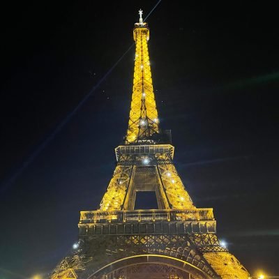 Torre Eiffel iluminada de noche en París, Francia en Europa vista desde la base con luces doradas y cielo oscuro estrellado . Foto tomada por Valen para su blog de viajes